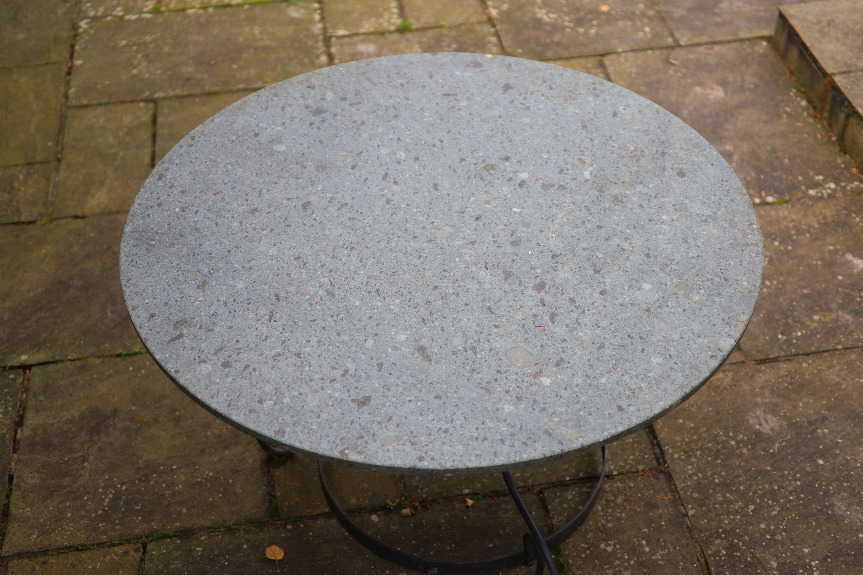 A wrought iron garden table with circular green marble top, width 123cm height 75cm